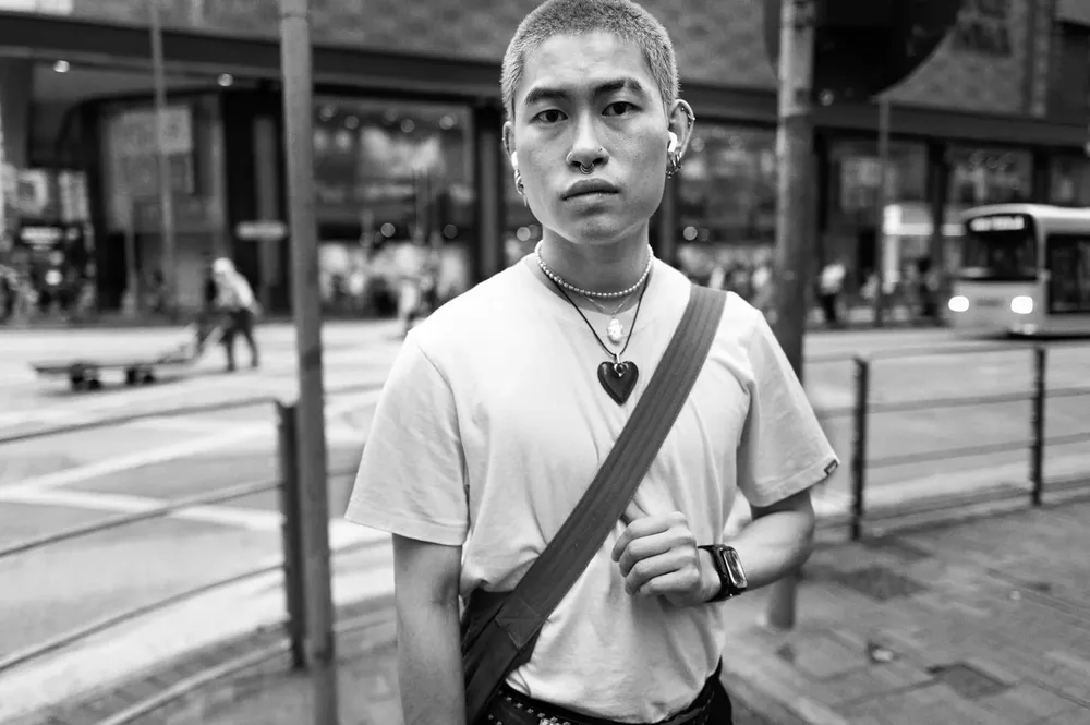 A man wearing a cross-body bag looks toward the camera at a crossing